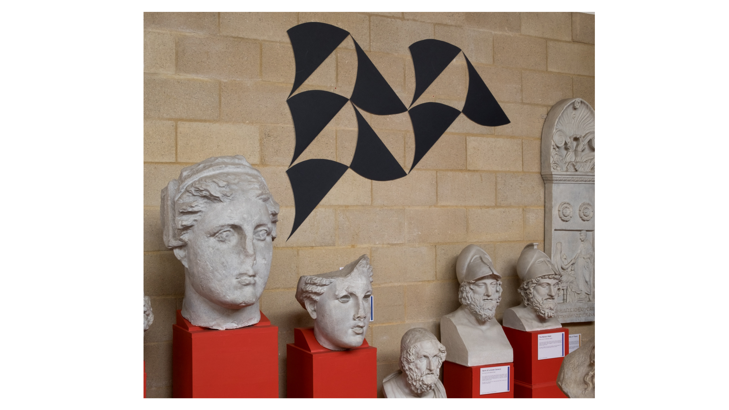 Black shapes reminisent of the mosaic at the baths of Caracalla, mounted on the wall above plaster casts