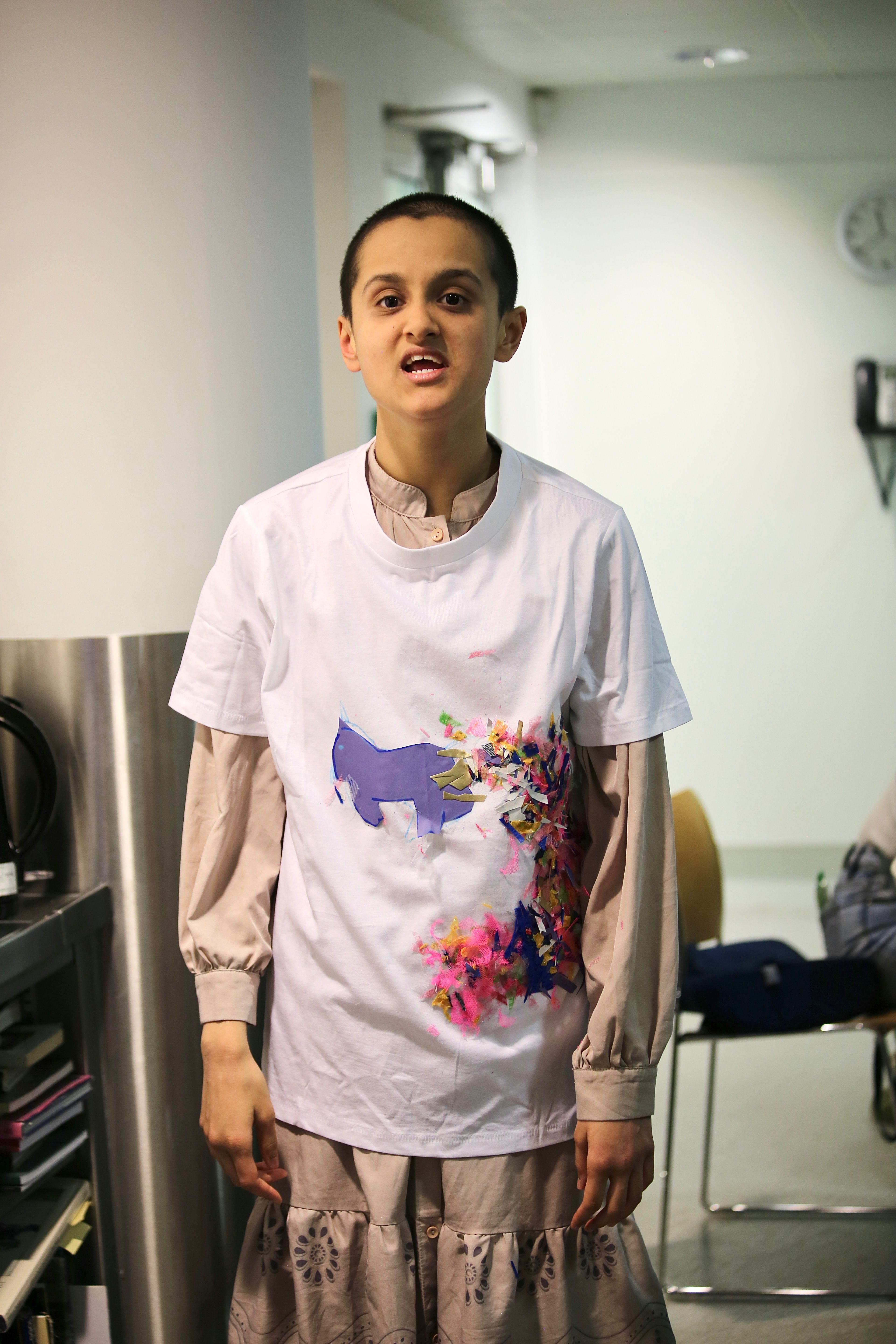 Khadija stands and wears her white t-shirt collage creation.