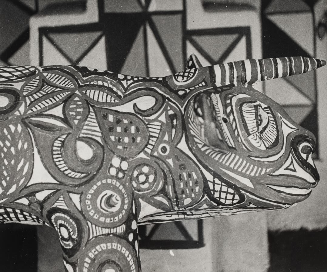 Close-up of a painted sculptural animal head with horn-like projections, covered in intricate swirling and geometric patterns.