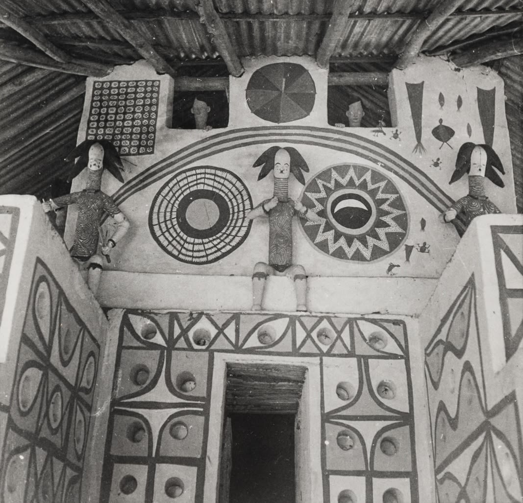 Interior or façade view showing sculpted figures positioned above a doorway, surrounded by circular and geometric painted designs on the wall.