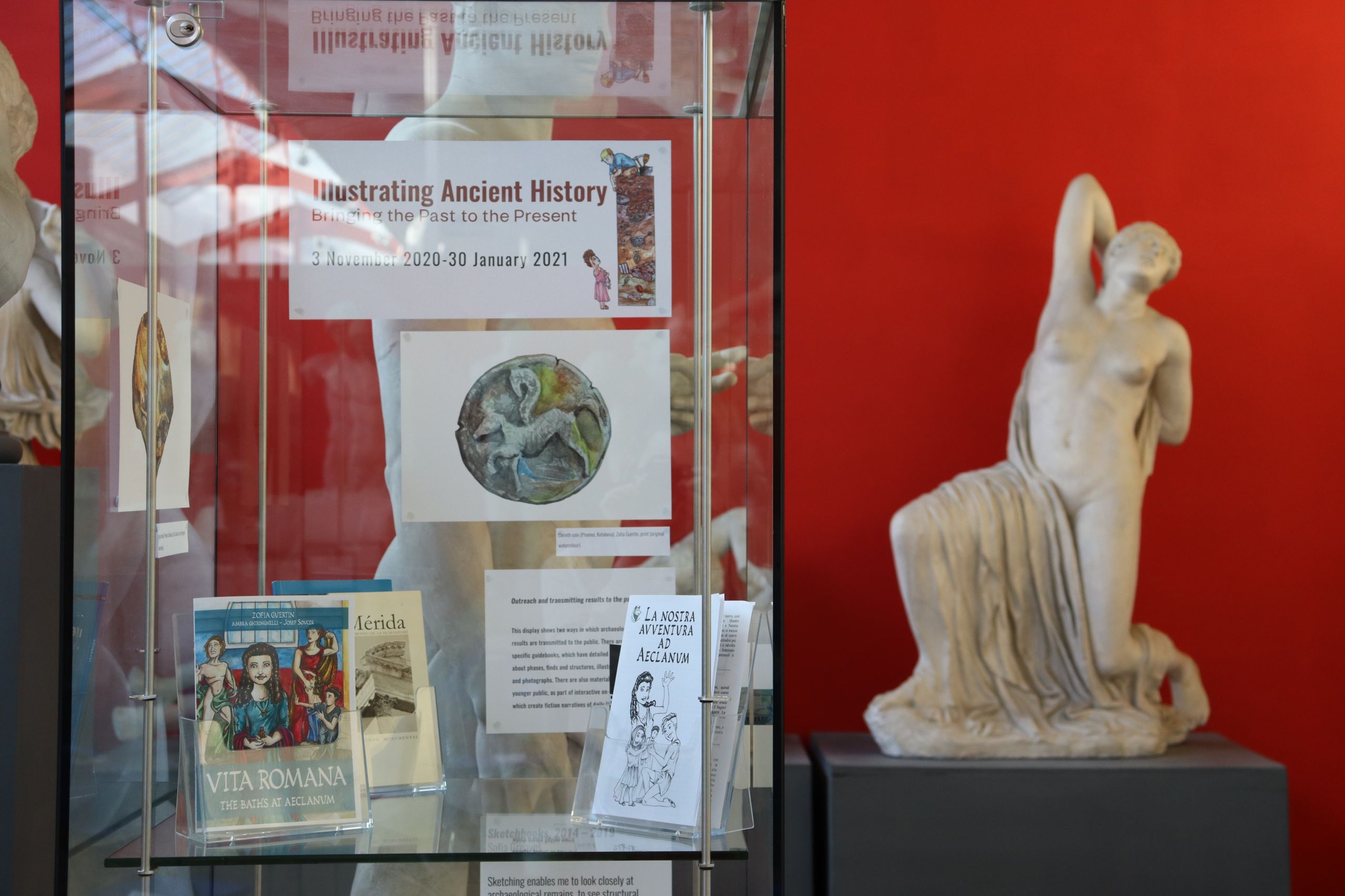 Photograph of a display case filled with booklets. Some are aimed at families and have artwork from the exhibition on the cover, the other is a more traditional guidebook with a photograph of the site.