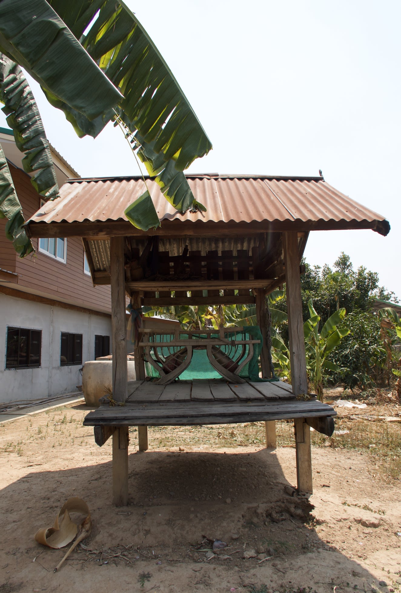 The shrine is made of four wooden posts, wooden planks on the base, and has a corrugated iron roof. On the base of the shrine is a wooden howdah - a chair used for passengers sitting on an elephant's back. The top level of the shrine is dark but holds a Pakam rope. 