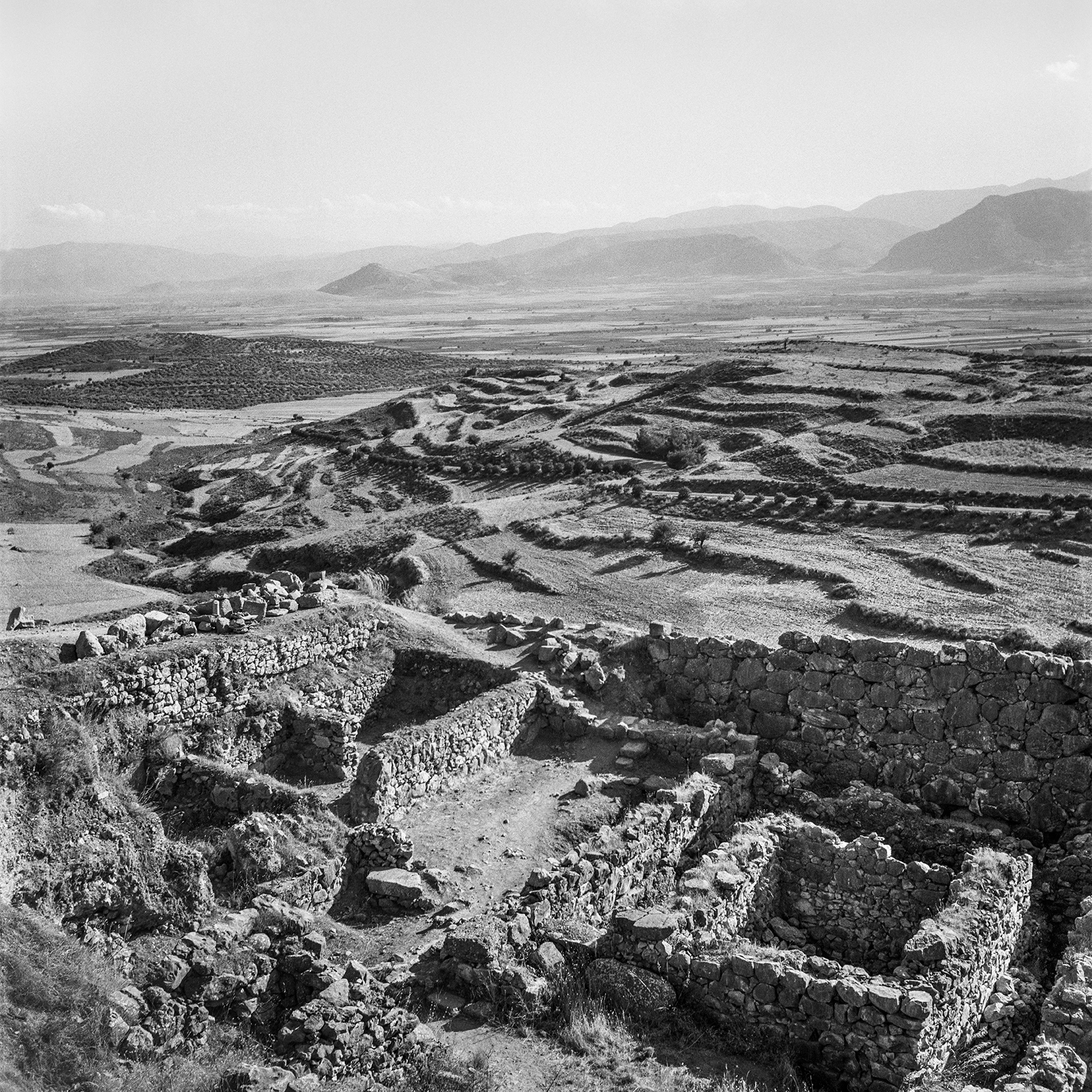 The landscape with ruins of square stone buildings.