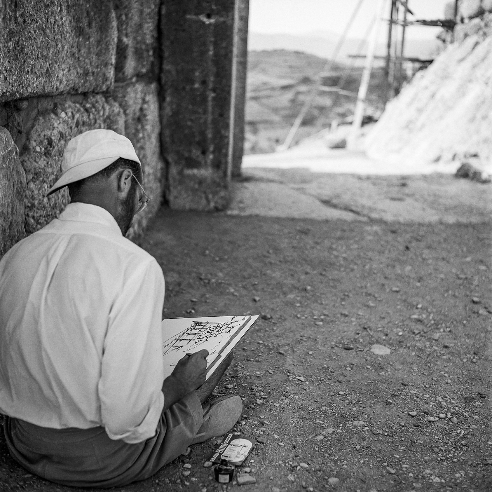 A man sits of the floor sketching
