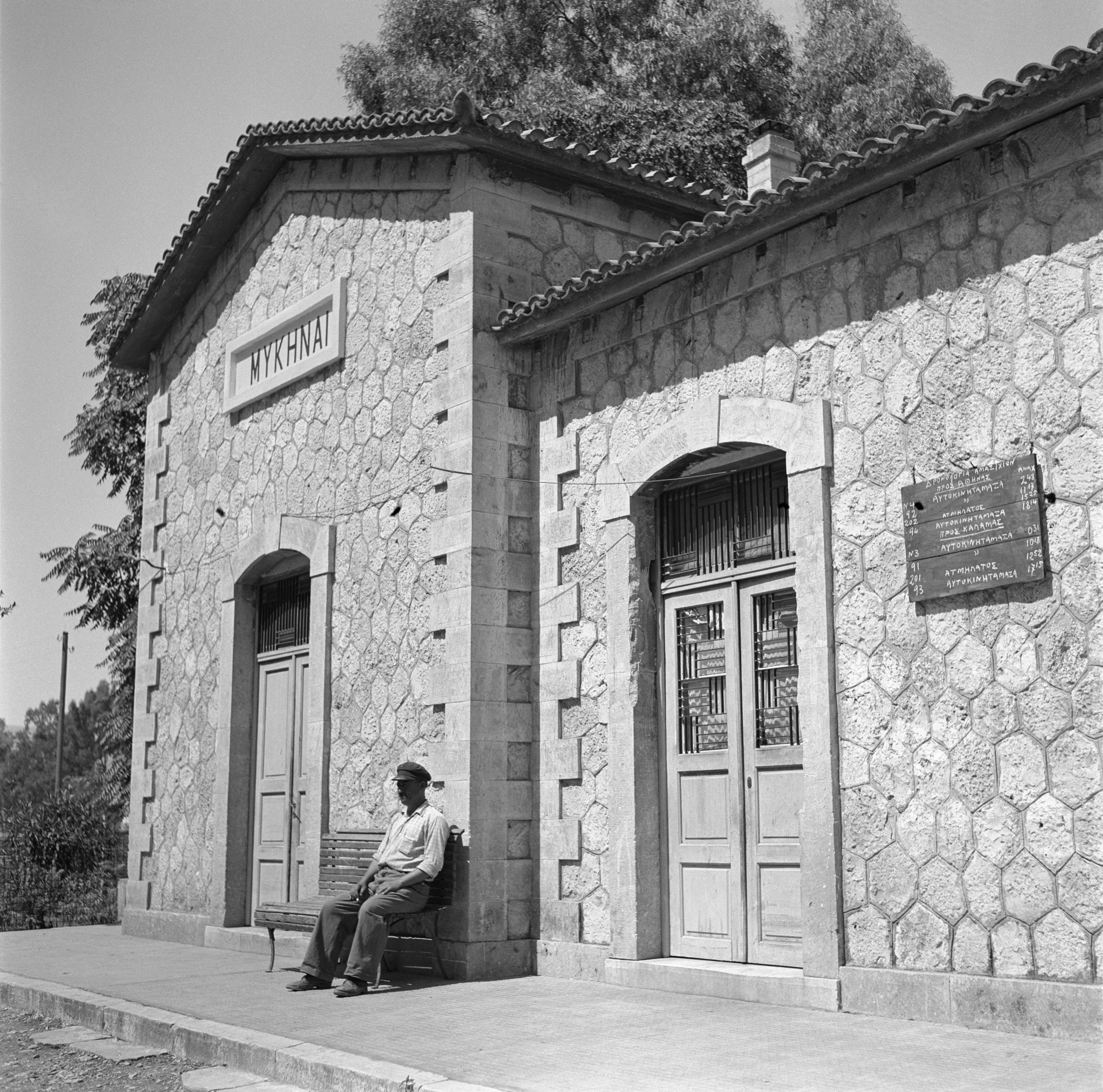 A man sits outside of a train station.