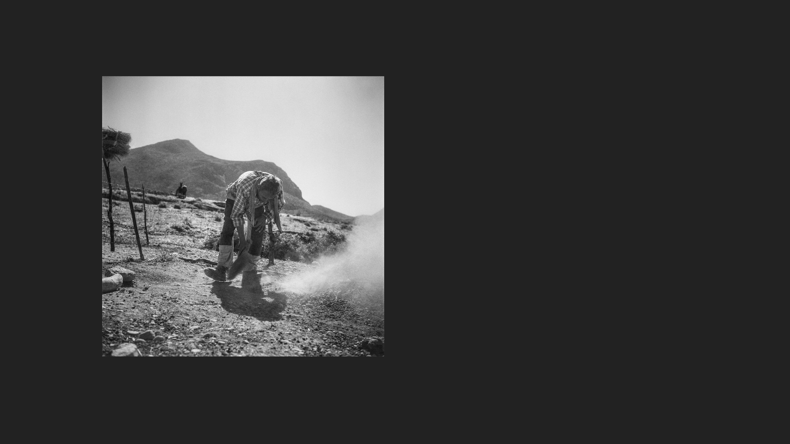 Dust rises from where a man is brushing the ground.
