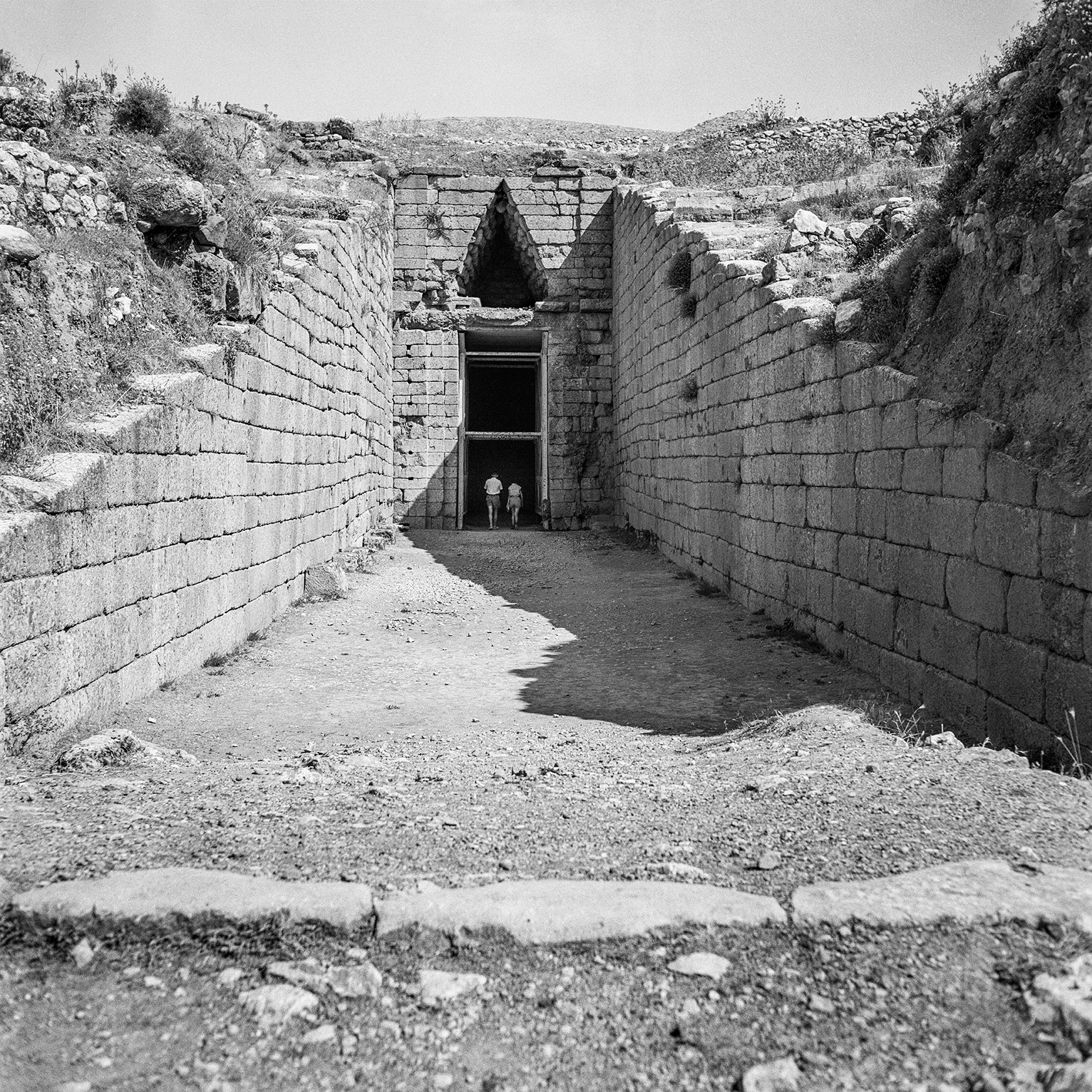 In the distance two people walk through an ancient entrance