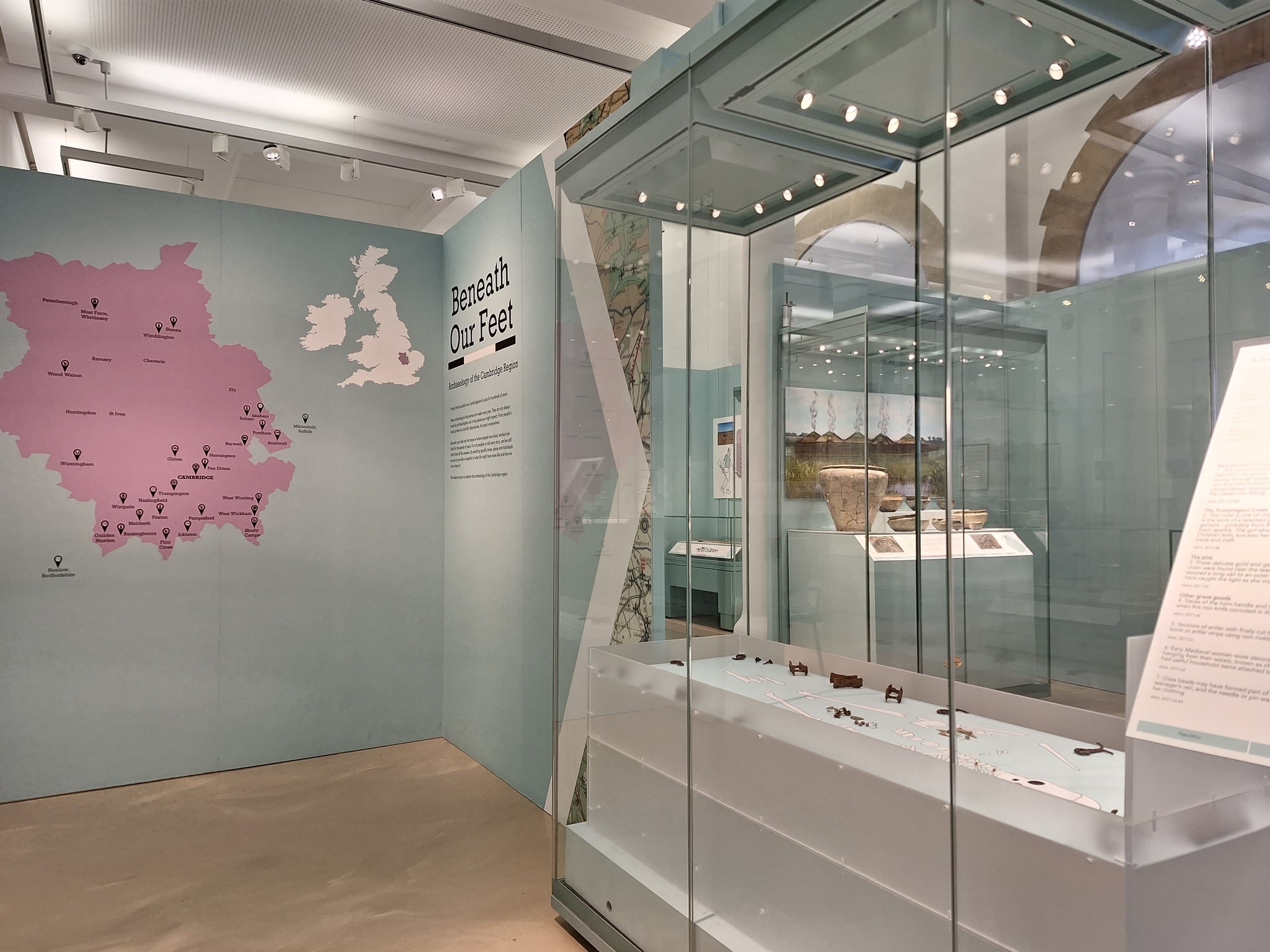 The Beneath Our Feet display at the Museum of Archaeology and Anthropology, which includes a map of the UK and Cambridge on one side and glass cases of objects on the other.