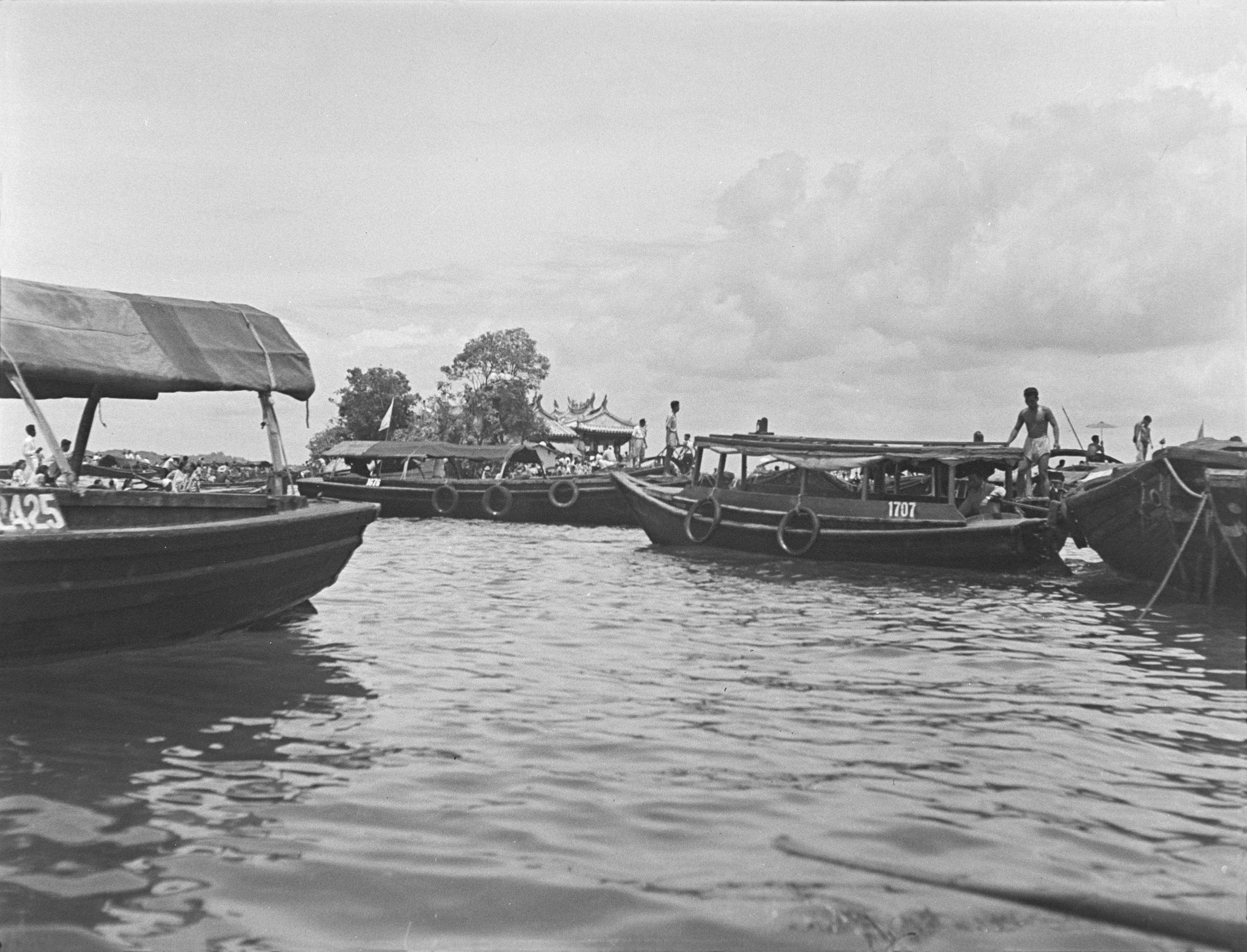 A few boats in the sea, with the Kusu Tua Pek Kong Temple is visible in the background.