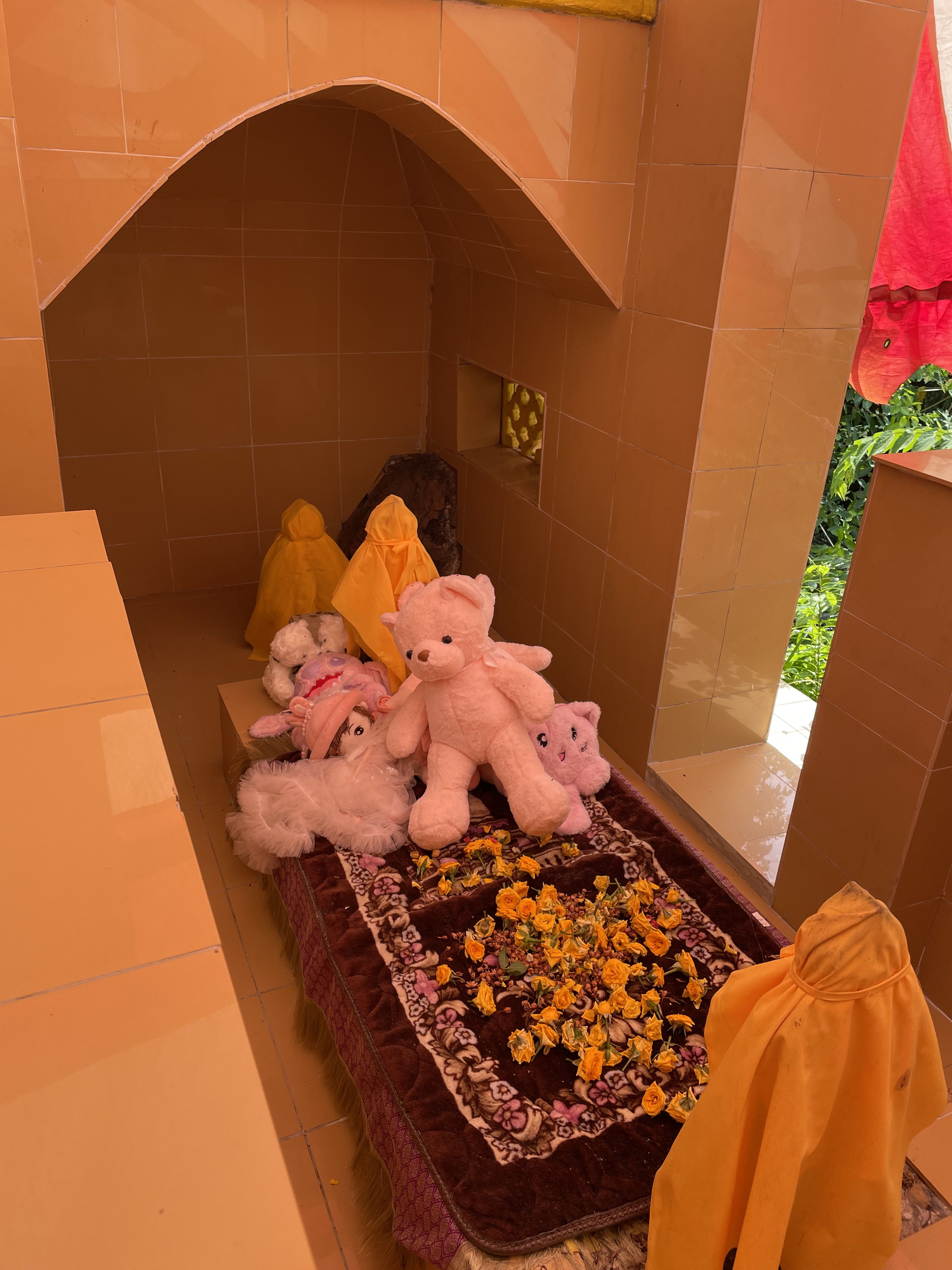 Plush toys and dolls placed on top of a raised rectangular structure covered in a velvet cloth.