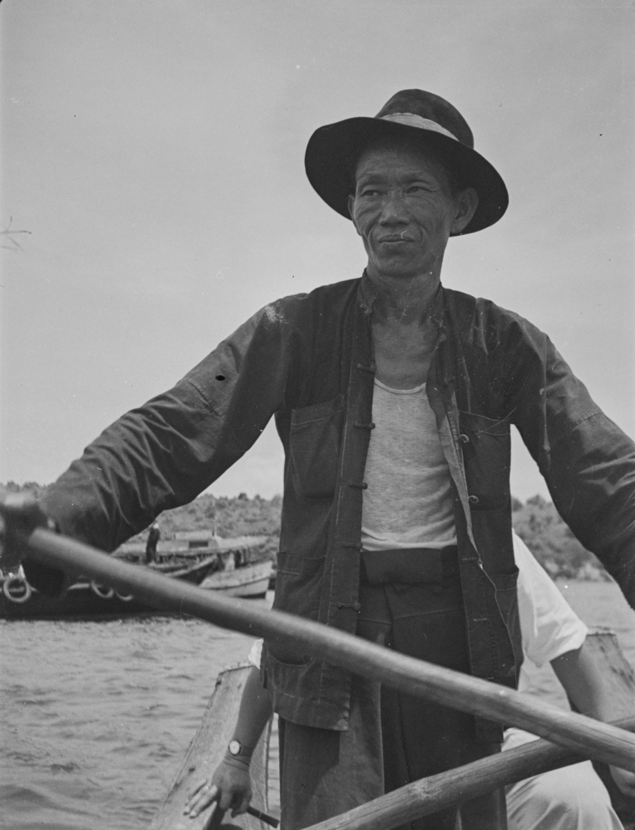 Boatman at Pulau Kusu (Kusu Island) holding onto a long pole, possibly an oar.