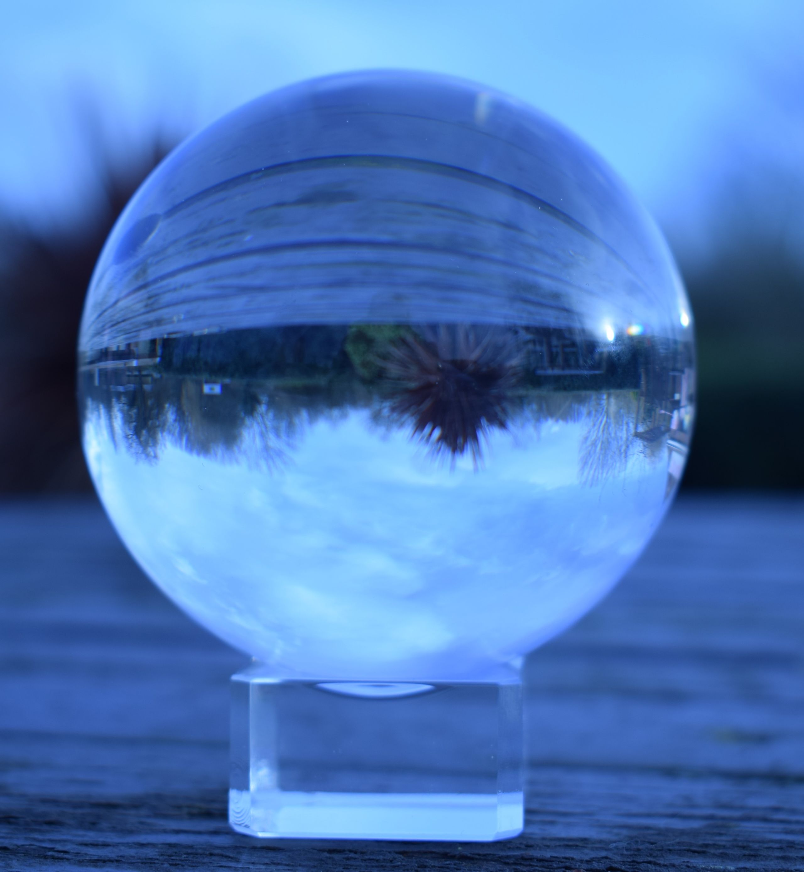 A glass sphere on a table outside, reflecting the landscape upside down.