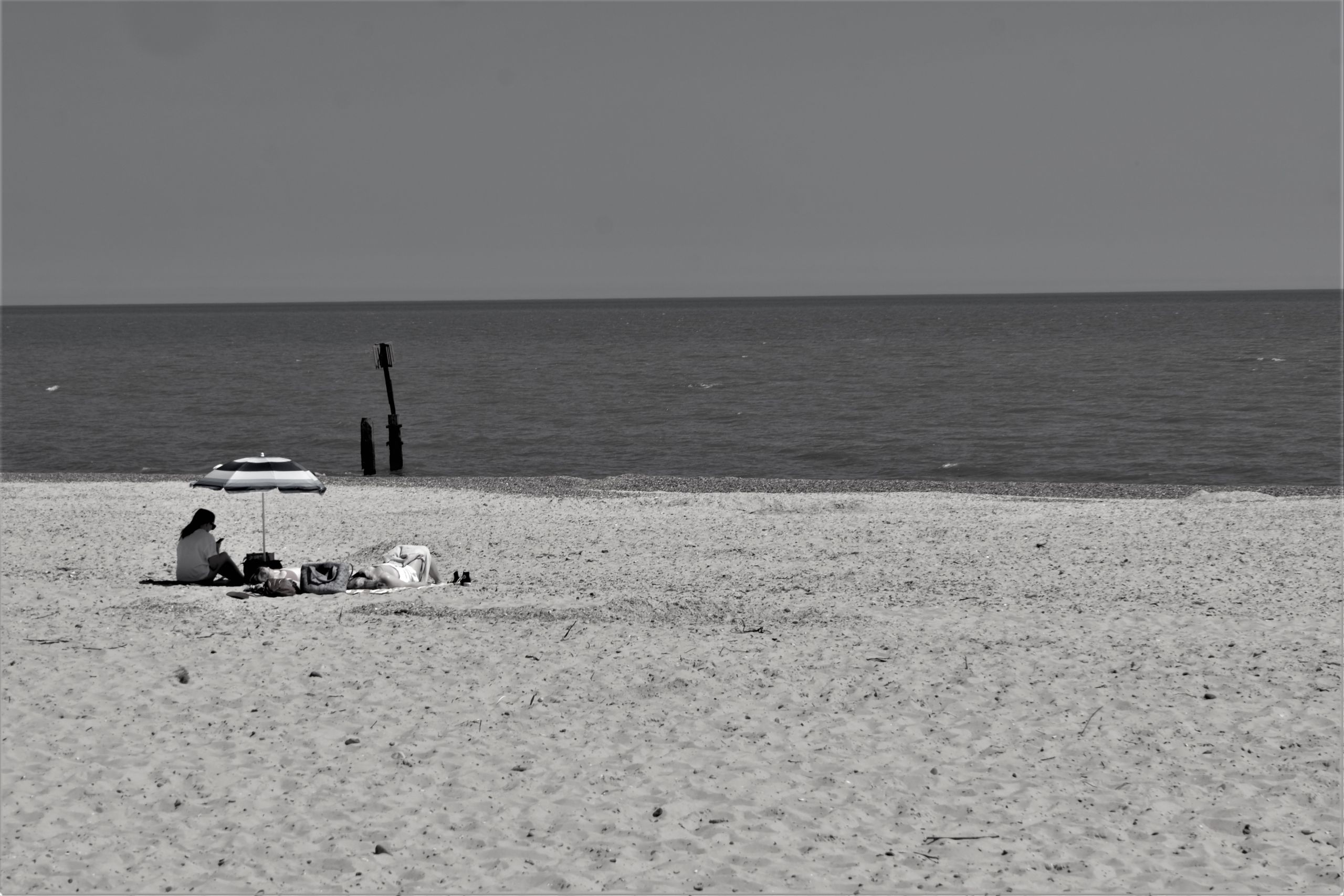 two people under an umbrella on the beach. Greyscale